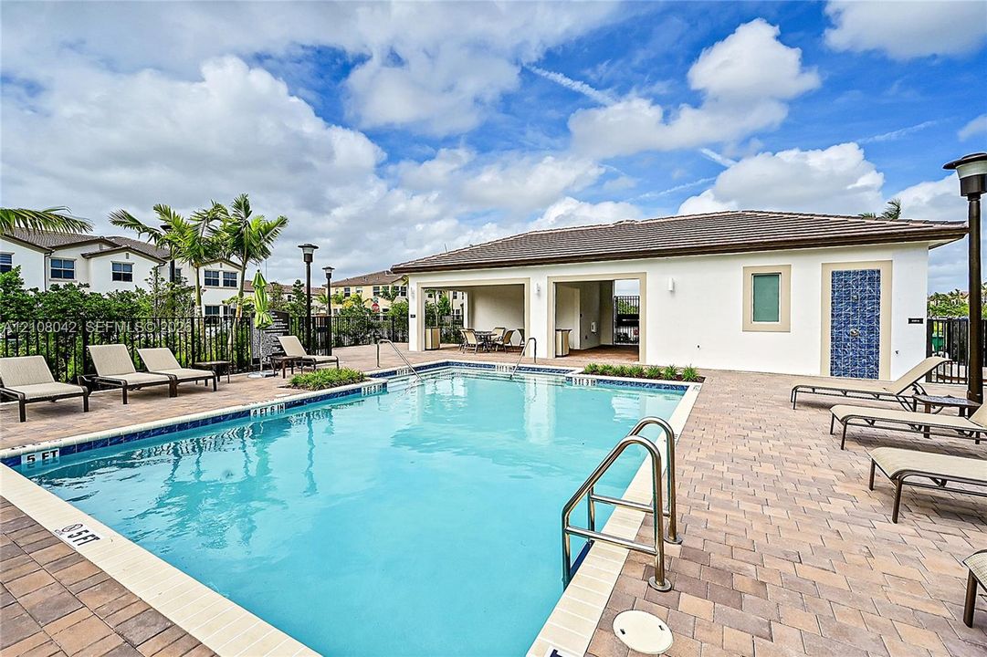Swimming pool featuring a paver stone deck, metallic pool ladder, and covered outdoor patio area