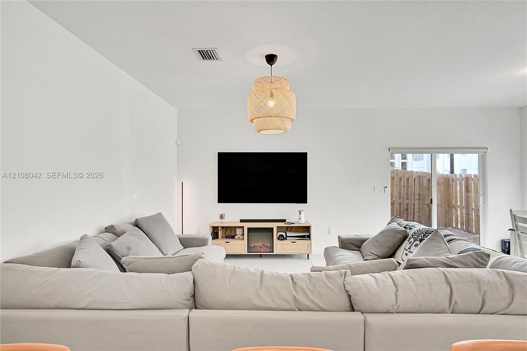 Woven textured pendant light, neutral wall palette, and sliding glass door with exterior access