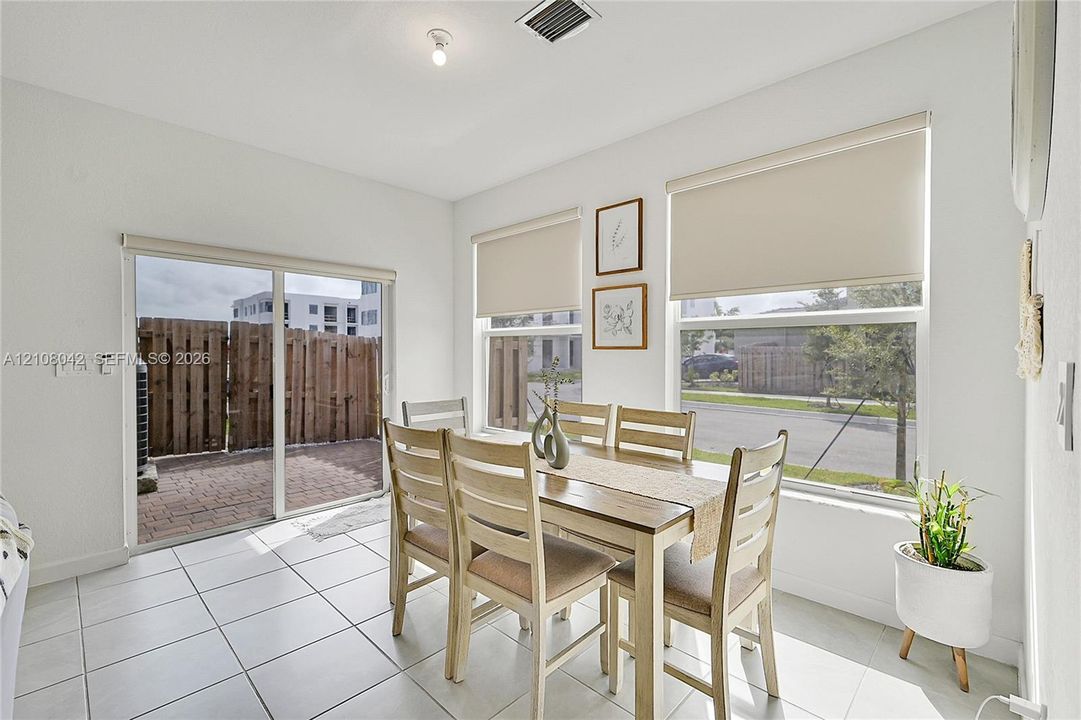 Ceramic tile flooring, sliding glass door with exterior access, and large windows with integrated roller shades