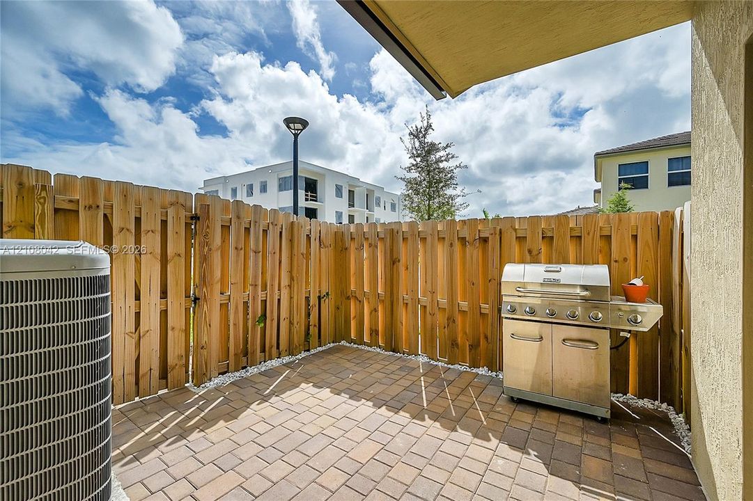 Private patio featuring paver flooring, wood-finish privacy fencing, and a stainless steel built-in grill