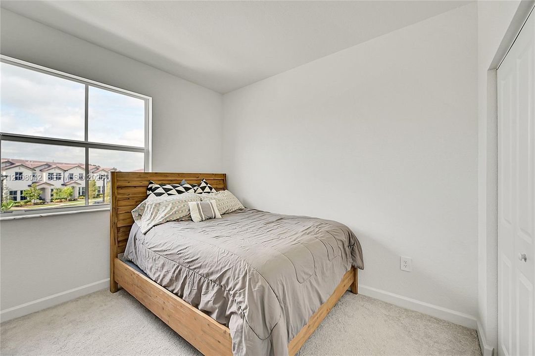 Neutral-toned room featuring wall-to-wall carpeting, a large single-pane window, and a white six-panel closet door