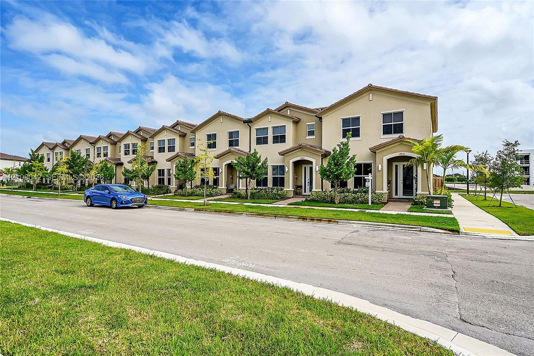 Multi-unit exterior featuring stucco siding, multi-gabled rooflines, covered entryways, and concrete sidewalks