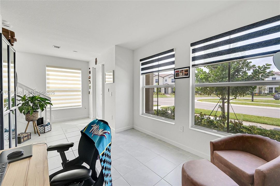 Bright room featuring large windows, neutral-tone tile flooring, and white interior walls