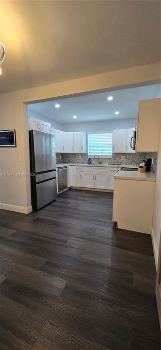 Kitchen featuring white shaker-style cabinetry, stainless steel appliances, recessed ceiling lighting, wood-finish flooring, and a patterned tile backsplash