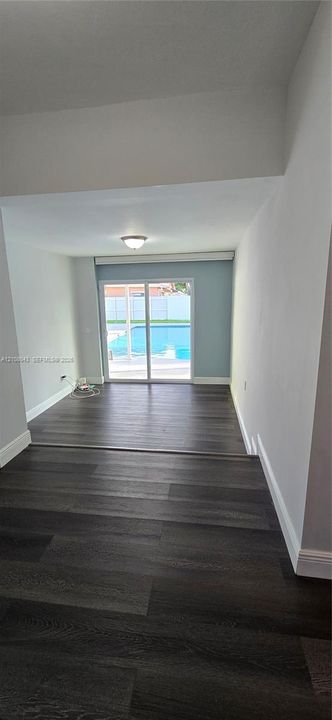 Interior featuring wood-finish flooring, recessed lighting, and sliding glass doors revealing an outdoor swimming pool