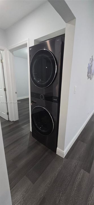 Stackable laundry unit with black metallic finish and wood-finish flooring