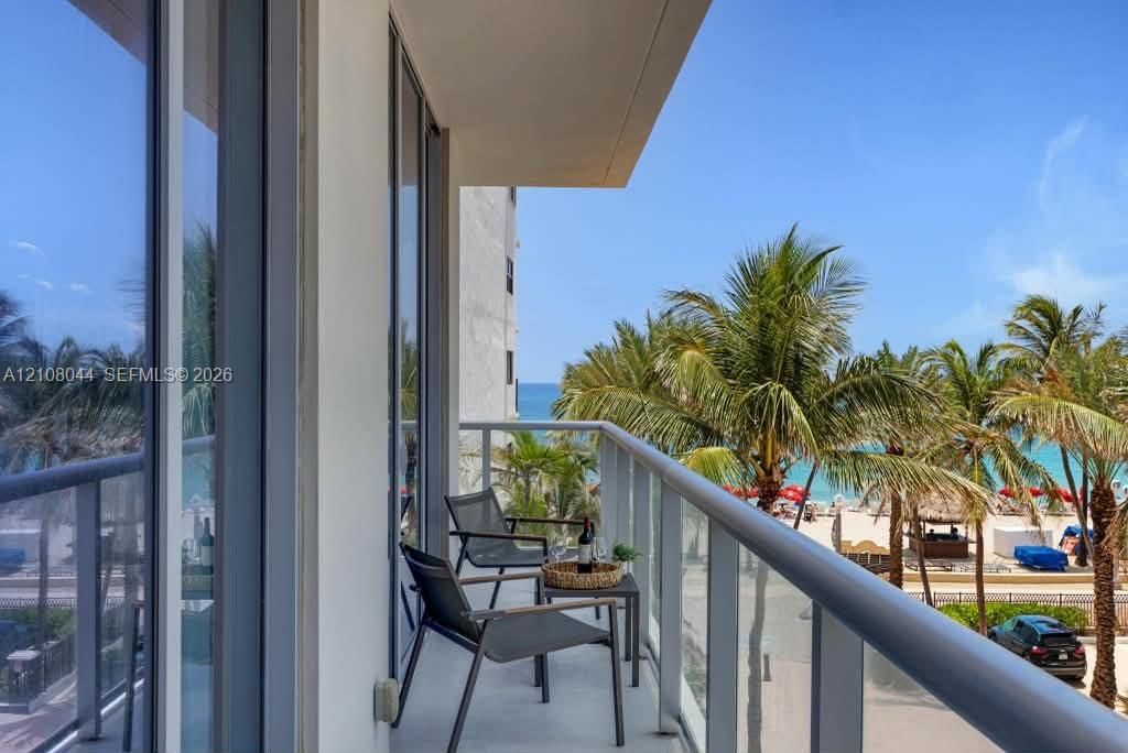 Covered balcony featuring metal railing, full-height glass door, and exterior floor tiling