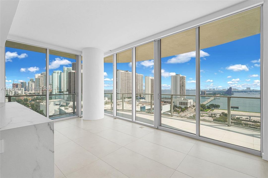 Floor-to-ceiling windows, white tile flooring, built-in counter with marbled finish, and roller shades