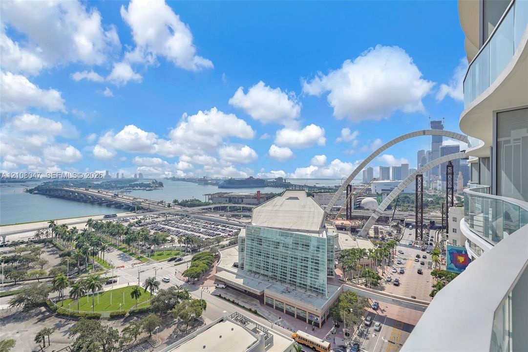 Curved balcony with glass railing, providing an expansive city and water backdrop