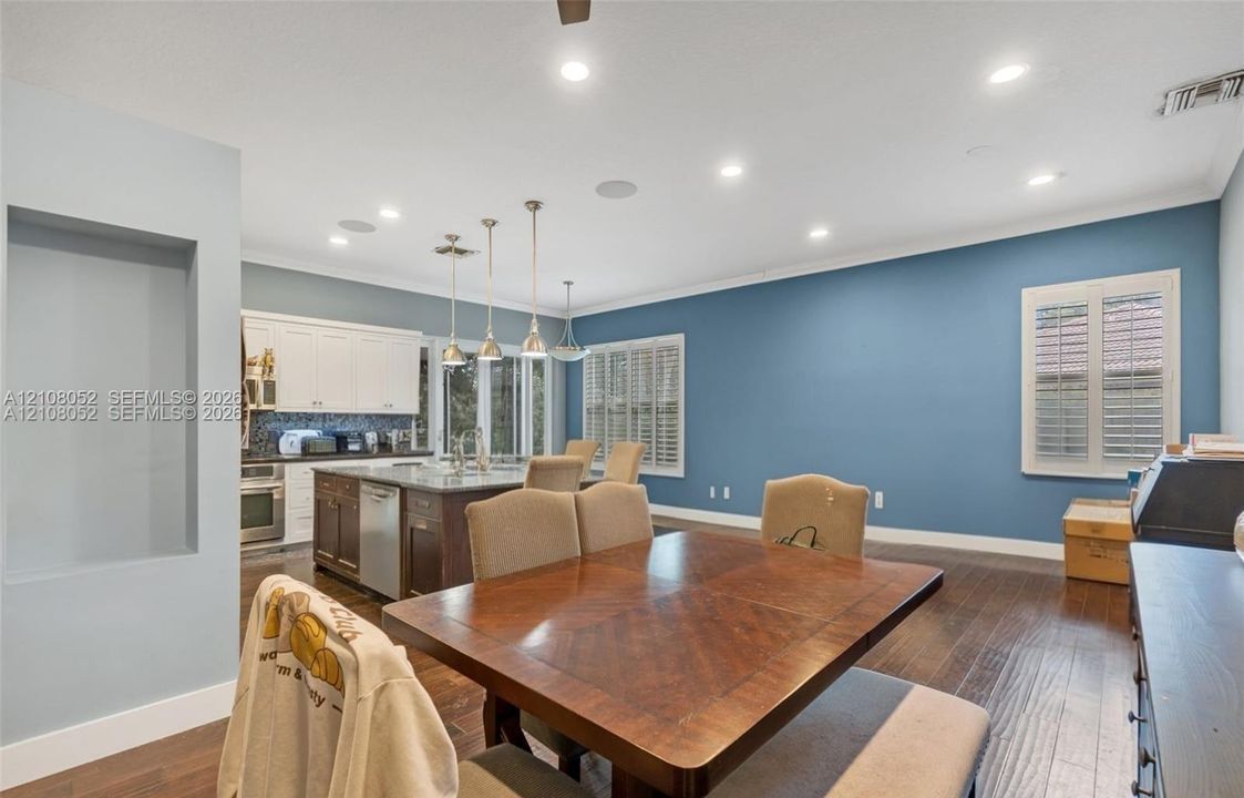 Kitchen featuring a center island, recessed ceiling lighting, three pendant lights, wood-finish flooring, and built-in wall niche