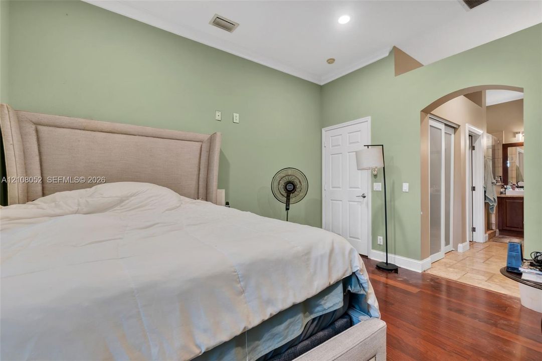 High-ceilinged room featuring wood-finish flooring, recessed lighting, and a distinct architectural archway