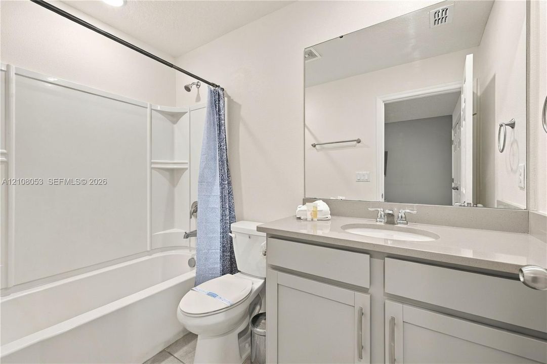 Bathroom featuring a vanity with a light-toned countertop, integrated oval sink, chrome dual-handle faucet, and an expansive wall-mounted mirror