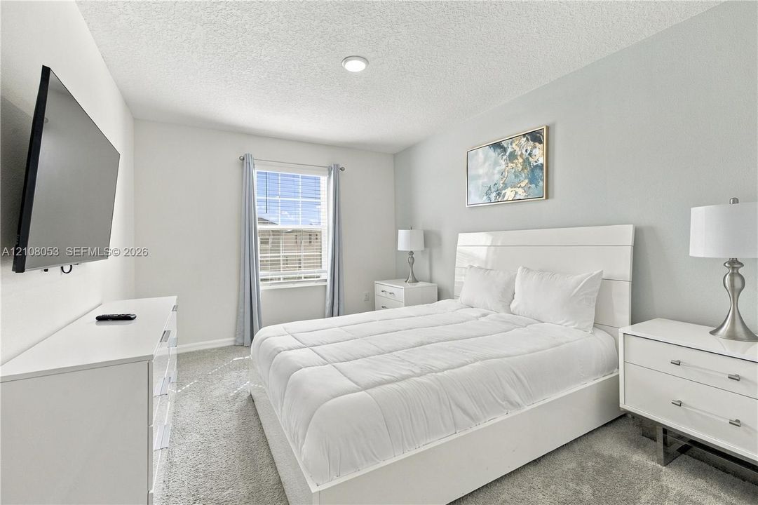 Neutral-toned interior featuring wall-to-wall carpeting, textured ceiling finish, and a single-hung window with built-in blind hardware