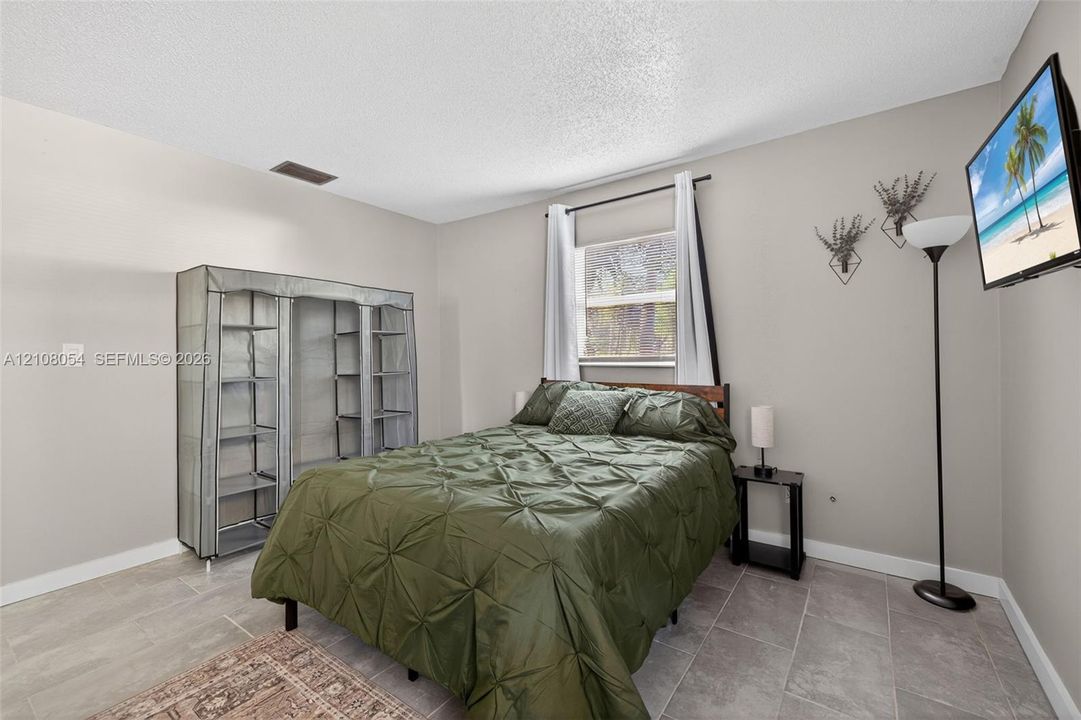 Neutral-toned interior featuring large-format ceramic tile flooring and a single-pane window