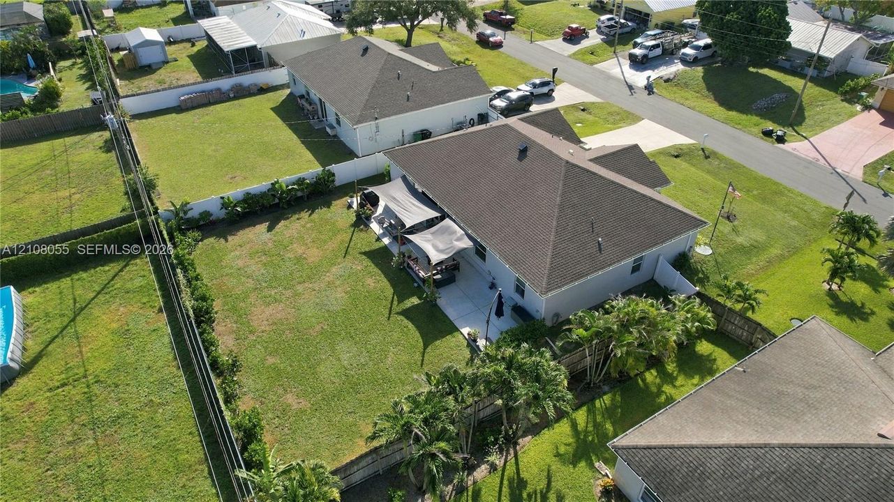 Aerial perspective of a property featuring a concrete patio, fenced backyard, and hipped roofline