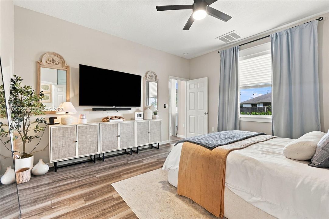 Neutral-toned interior featuring wood-finish flooring, a ceiling fan with integrated lighting, and horizontal blinds