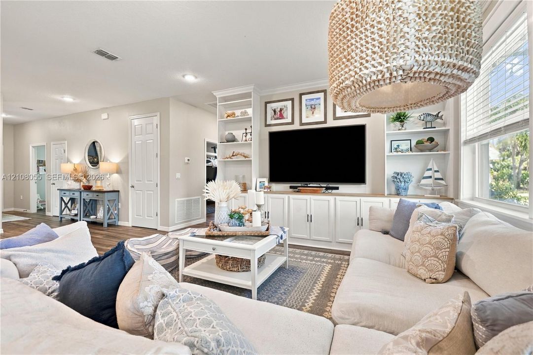 Custom floor-to-ceiling built-in cabinetry featuring open shelving and base storage, recessed lighting, and a textured woven drum pendant light