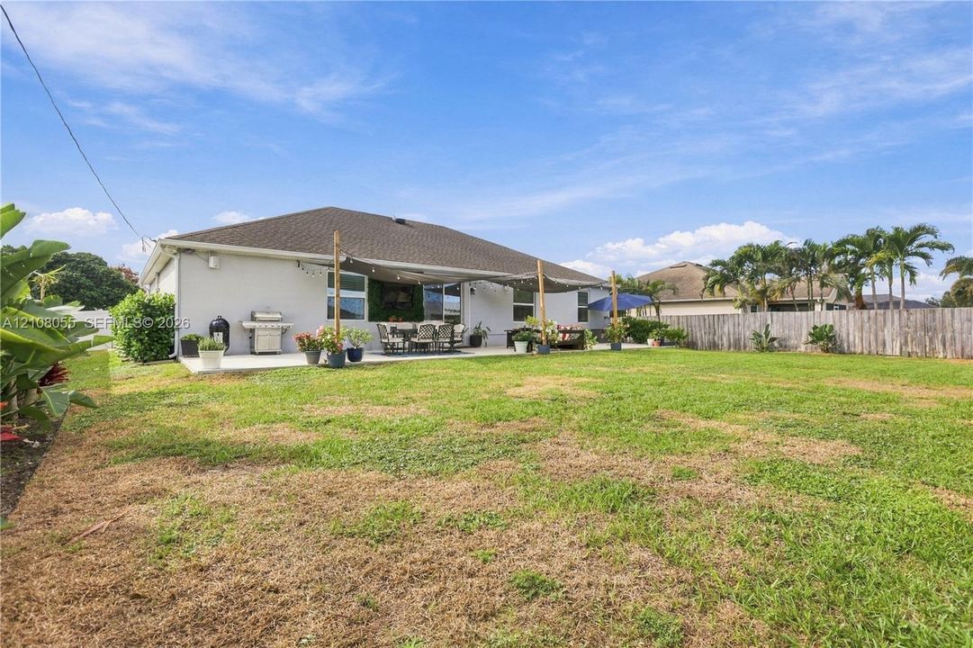 Backyard featuring an expansive lawn, concrete patio, and perimeter wood privacy fencing