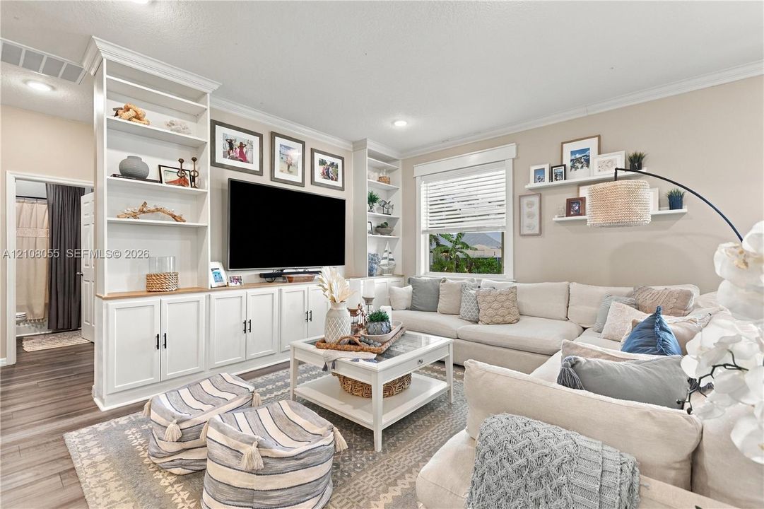 Built-in floor-to-ceiling white cabinetry, wood-finish flooring, recessed lighting, and white floating wall shelves