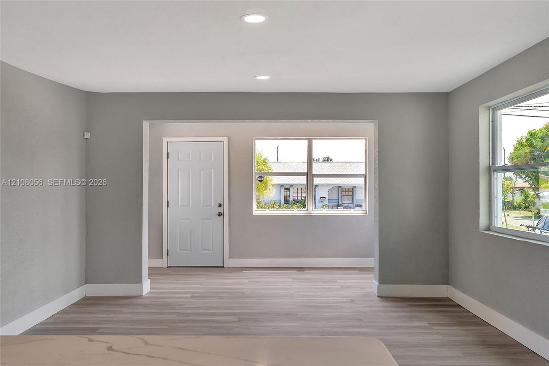 Interior space featuring wood-finish flooring, recessed lighting, neutral wall paint, white trim, and oversized windows