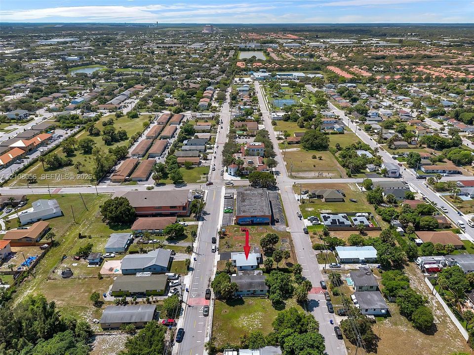 Aerial perspective highlighting a corner lot location with direct street access, proximity to commercial infrastructure, and established landscaping