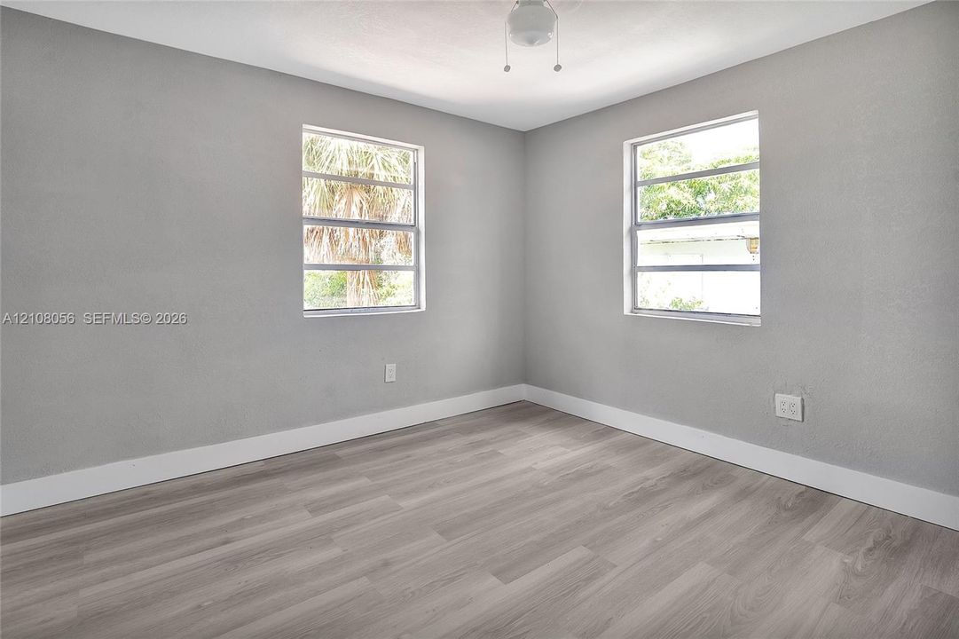 Neutral-toned interior space featuring wood-finish flooring, two horizontal sliding windows, and a central ceiling-mounted light fixture