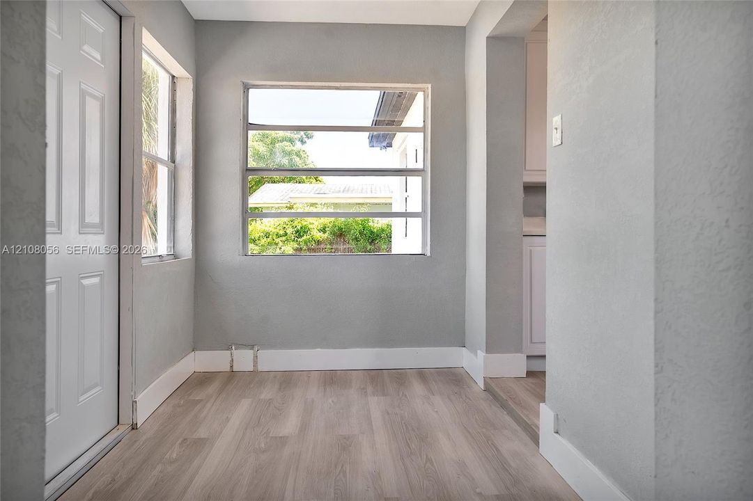 Neutral-toned interior space featuring wood-finish flooring, multi-pane windows, and a solid-panel door