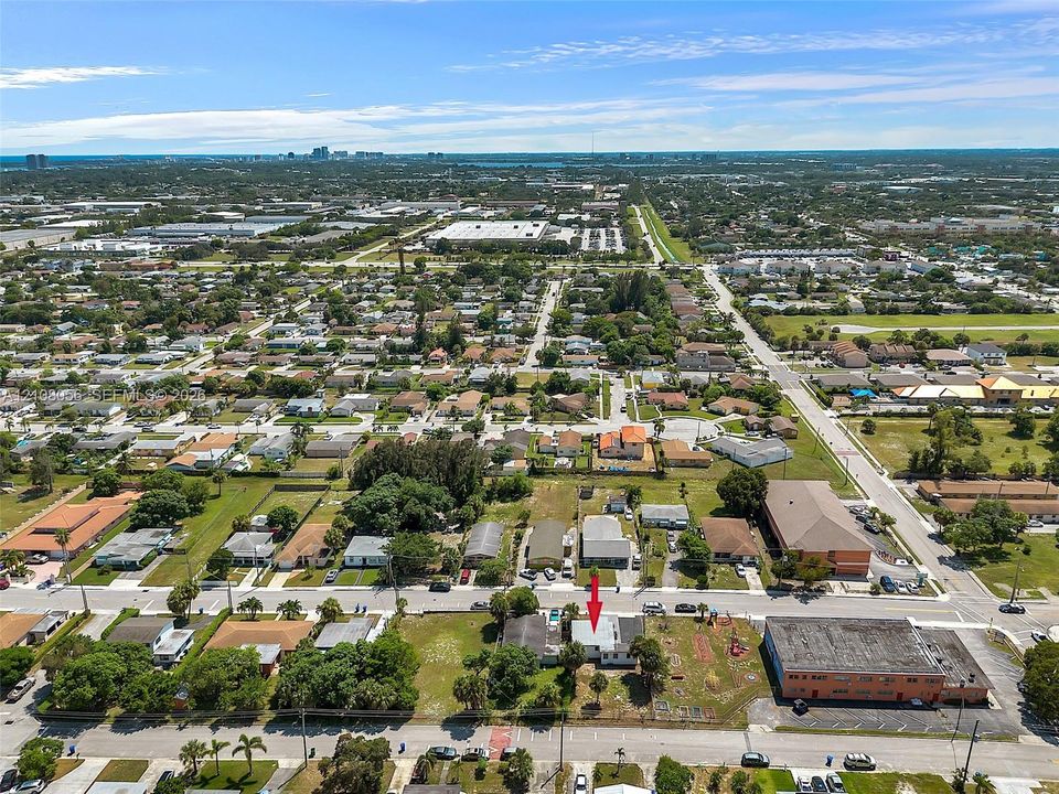 Aerial perspective of a corner lot property featuring a single-story structure, fenced perimeter, and established landscaping