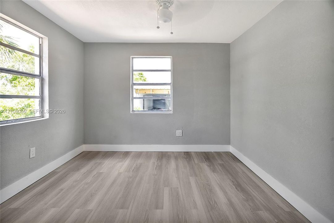 Room featuring wood-finish flooring, two horizontal-pane windows, and a central ceiling light fixture