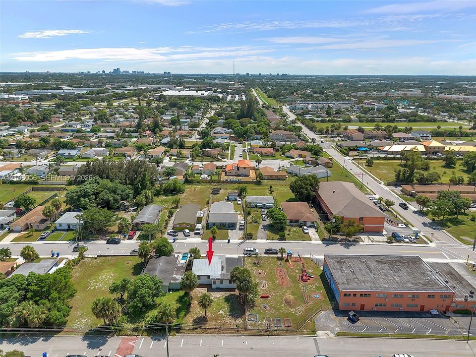 Aerial perspective featuring a single-story residence with a pitched roof, situated on a rectangular lot with mature palm trees