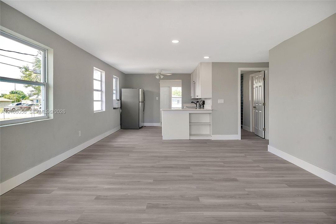 Open-concept interior featuring wood-finish flooring, recessed lighting, and white cabinetry with a built-in peninsula