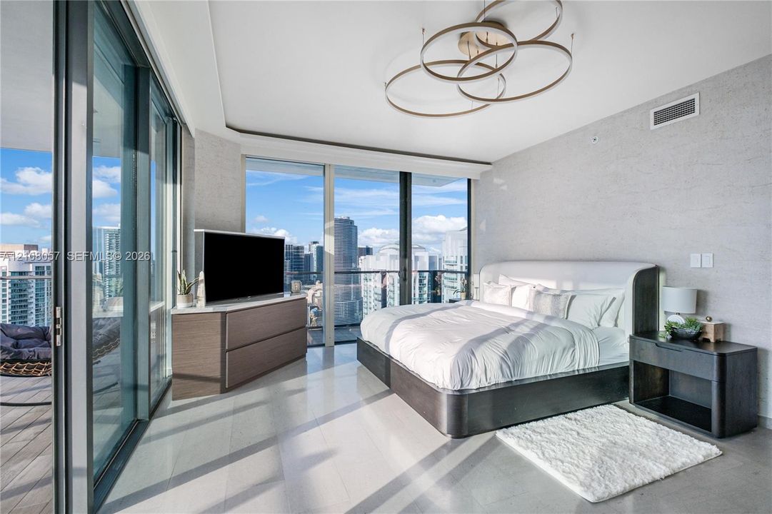 Floor-to-ceiling glass walls, expansive balcony access, polished stone flooring, custom orbital ceiling lighting, and textured wall finish