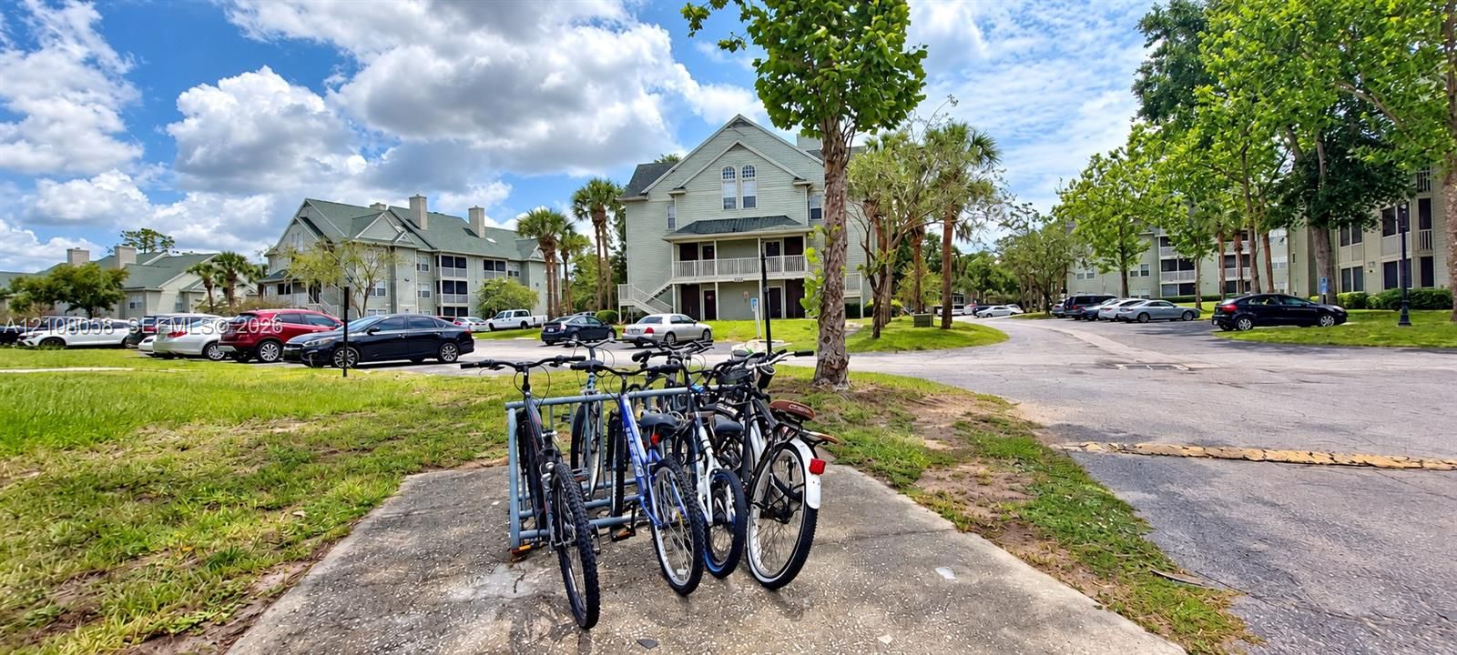 Multi-story residential buildings featuring gabled rooflines, covered entryways, and exterior staircases with paved parking areas and bicycle racks