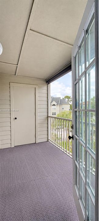 Covered balcony featuring horizontal lap siding, a secure storage closet, a white metal railing, and white-trimmed French doors