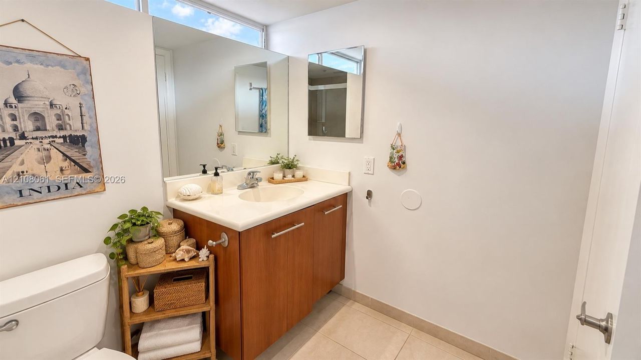 Bathroom featuring a wood-finish vanity with a stone-surface countertop, an integrated sink, polished metal hardware, and a large-format mirror
