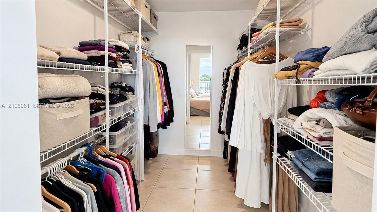Walk-in closet featuring floor-to-ceiling white wire shelving, multi-level hanging rods, and a wall-mounted full-length mirror