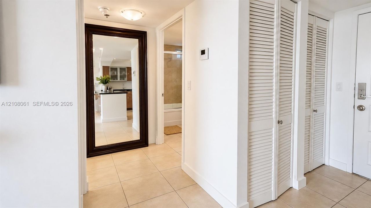 Neutral tile flooring, dual white louvered-door closets, and a ceiling-mounted flush light fixture