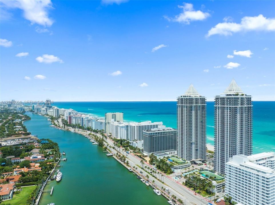 Aerial perspective featuring high-rise towers, proximity to the coastline, and a deep-water canal