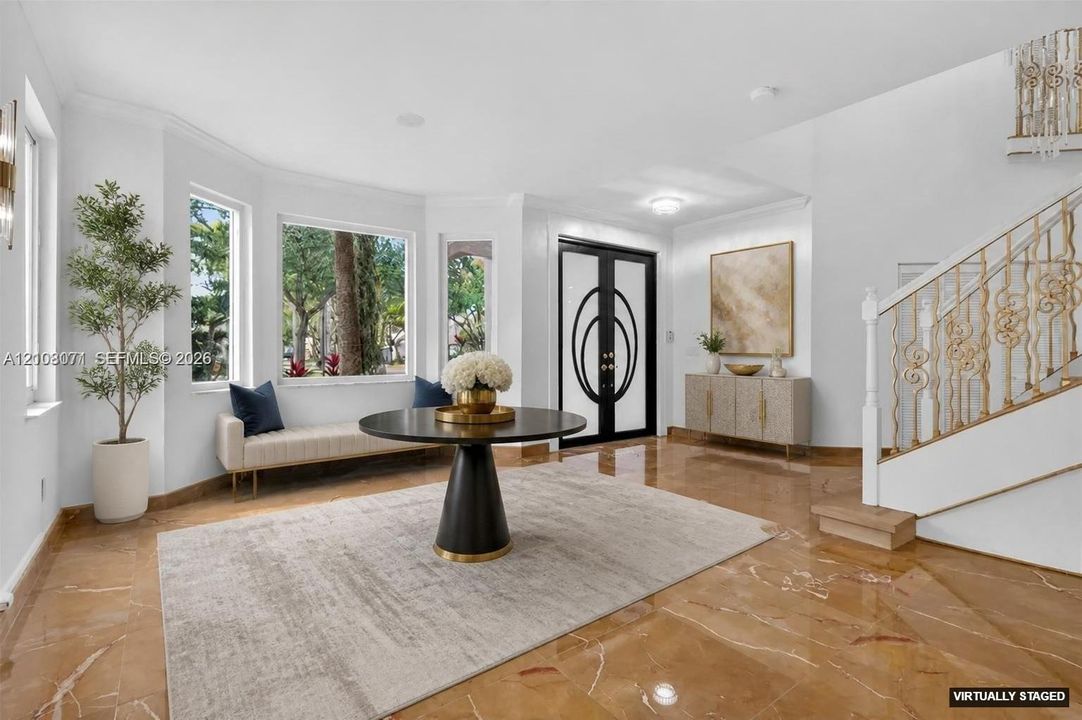 Foyer featuring polished stone flooring, bay windows, dual-entry doors with geometric glass inserts, and a decorative gold-tone metal stair railing