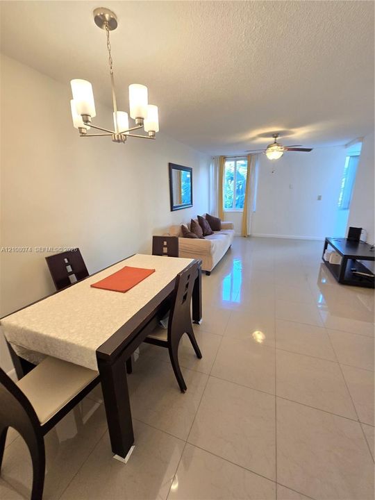 Large-format tile flooring, multi-light chandelier, and ceiling fan with integrated lighting