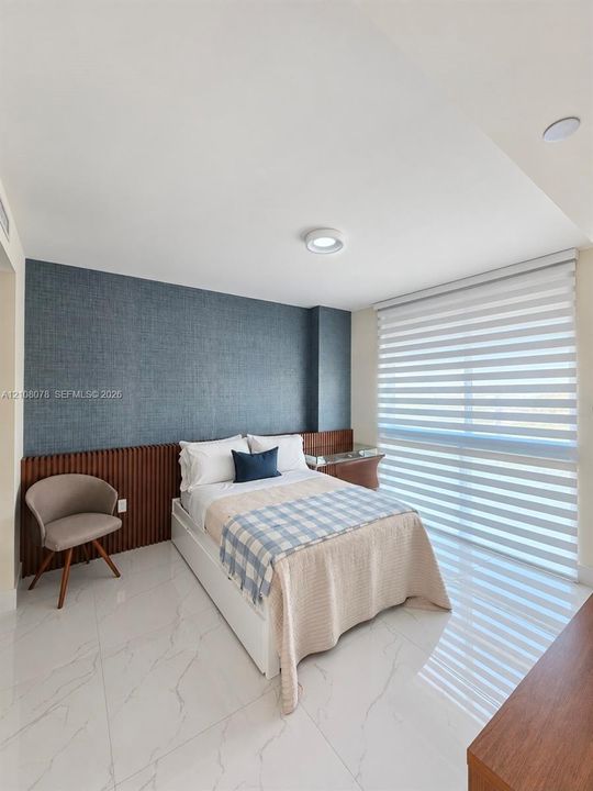Polished stone-look flooring, custom vertical wood-slat wall paneling, textured dark-toned accent wall, and horizontal dual-layer window treatments