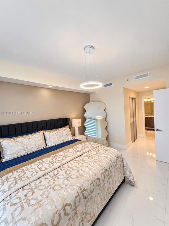 Polished stone flooring, recessed lighting, and a modern circular LED pendant fixture