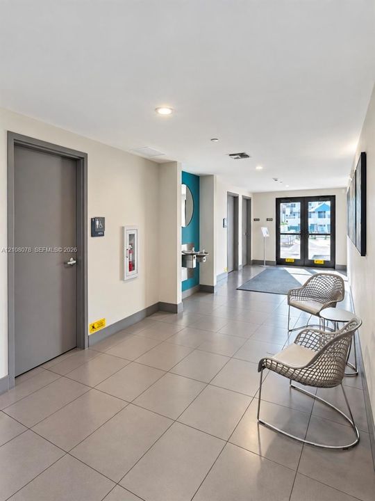 Common area featuring large-format ceramic tile flooring, recessed LED lighting, and metal-framed double glass entry doors