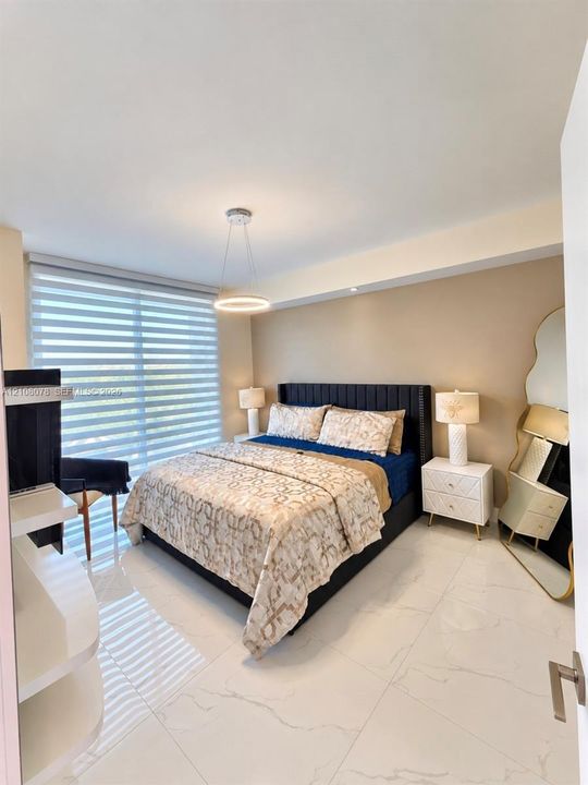 Large-format tile flooring, oversized window with adjustable roller shades, modern circular pendant lighting, and built-in white shelving
