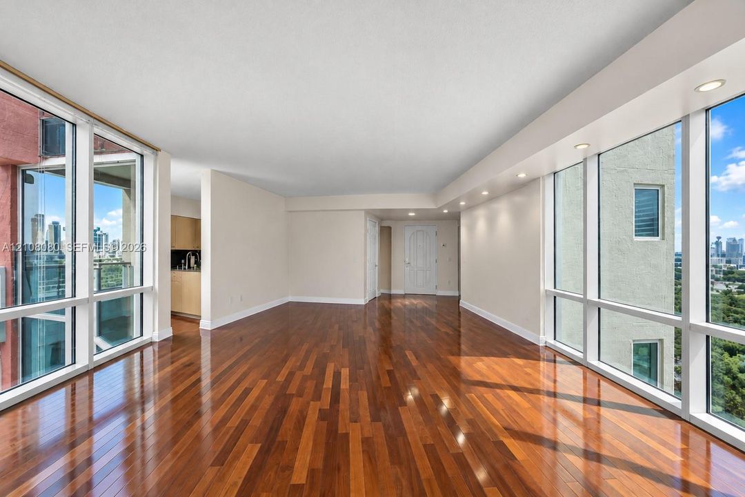 Open-concept living space featuring floor-to-ceiling windows, polished wood-finish flooring, recessed lighting, and expansive exterior scenery