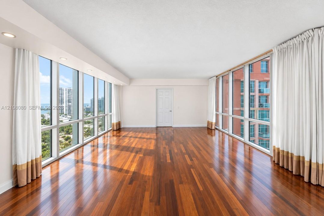 Expansive interior featuring floor-to-ceiling glass windows, wood-finish flooring, and recessed lighting