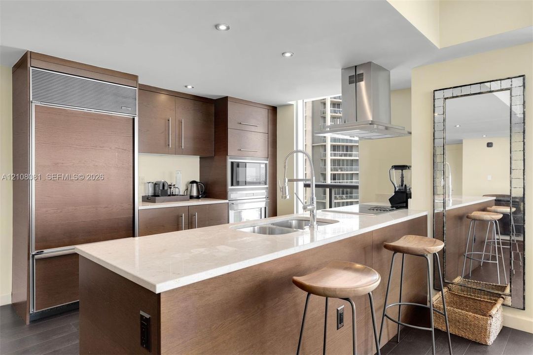 Kitchen featuring wood-finish cabinetry, stone-surface countertops, stainless steel appliances, stainless steel range hood, and recessed lighting