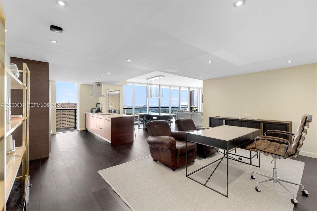 Open-concept interior featuring wood-finish flooring, floor-to-ceiling windows, recessed lighting, and kitchen island with integrated cabinetry