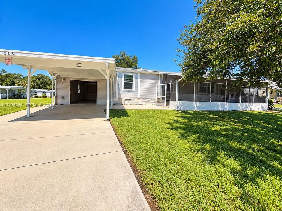 Exterior featuring a covered carport, attached screened-in porch, horizontal siding, stone-textured skirting, and a concrete driveway