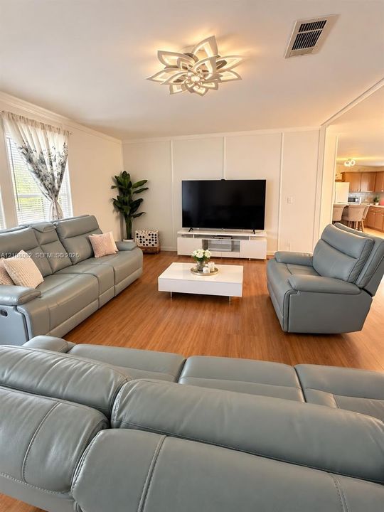 Living area featuring wood-finish flooring, decorative wall molding, and a contemporary petal-style flush-mount ceiling light